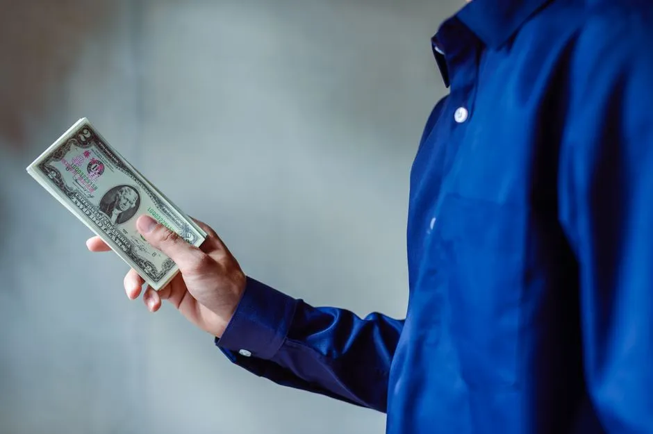 Person holding cash, illustrating a paycheck being deposited