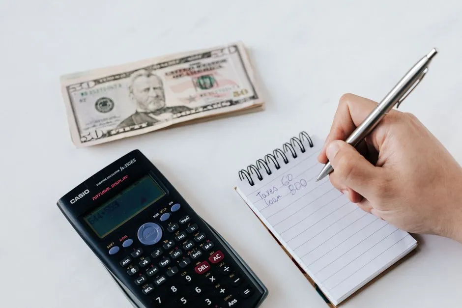 Person doing personal budgeting paperwork with a calculator and notebook